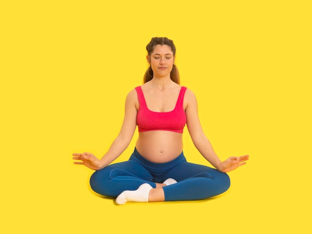 Young pregnant woman meditating in lotus pose