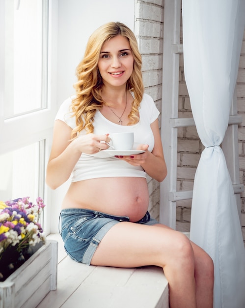 Young pregnant woman near window