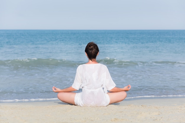 Young pregnant woman practicing yoga at sea