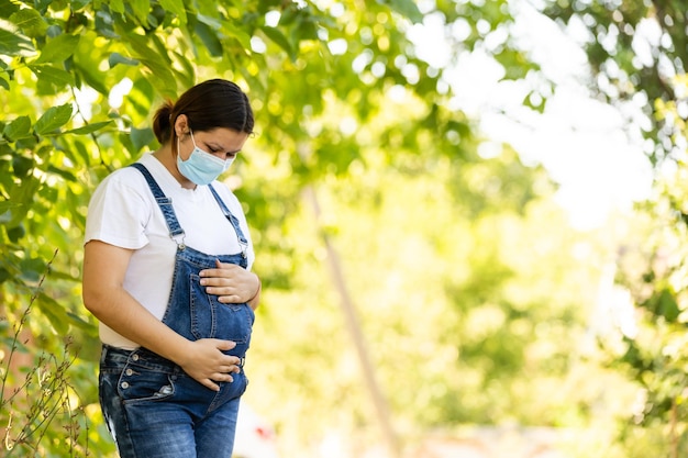 Young pregnant woman in protective medical mask covered her face. Virus protection and hygiene.