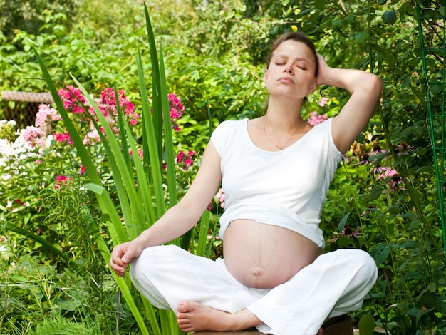 Young pregnant woman relaxing in a summer garden