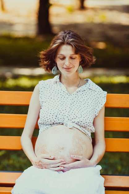 Young pregnant woman siting on a bench