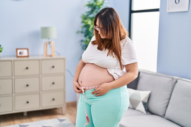 Young pregnant woman smiling confident measuring belly at home