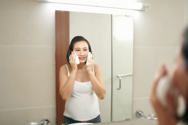 Young pregnant woman washing face