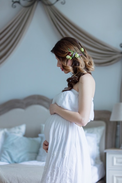 Young pregnant woman in white dress 