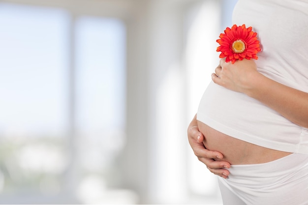 ぼやけた背景に花を持つ若い妊婦