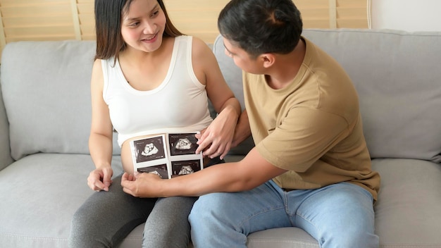 Young pregnant woman with husband holding ultrasound photo of newborn