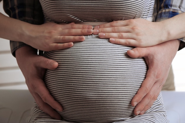 Young pregnant woman with husband touching belly close up