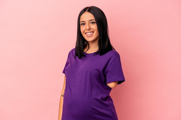 Young pregnant woman with one arm isolated on pink background happy, smiling and cheerful.