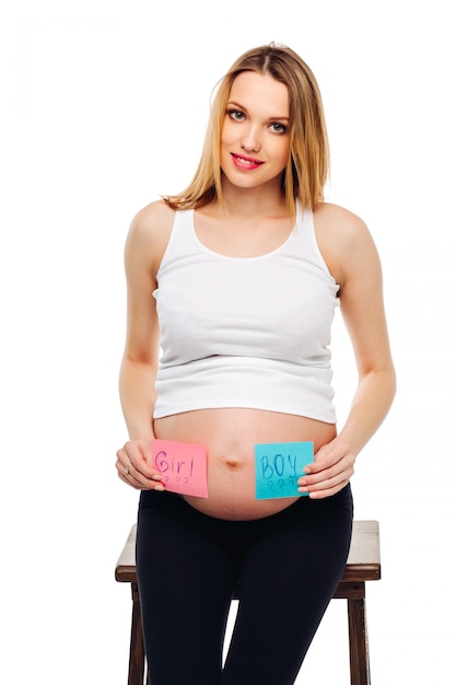 Photo young pregnant woman with a sticker and a question on it boy or girl concept. expectant mother.