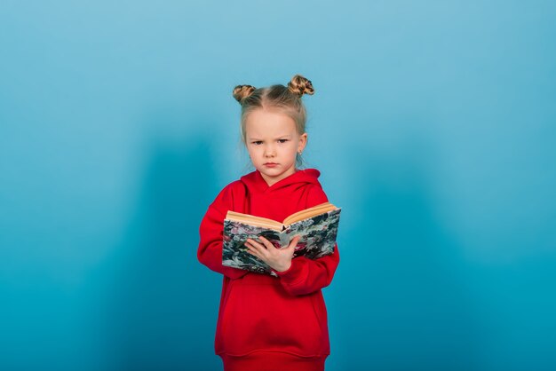 Photo young preschool child learns while reading a book, isolated on blue