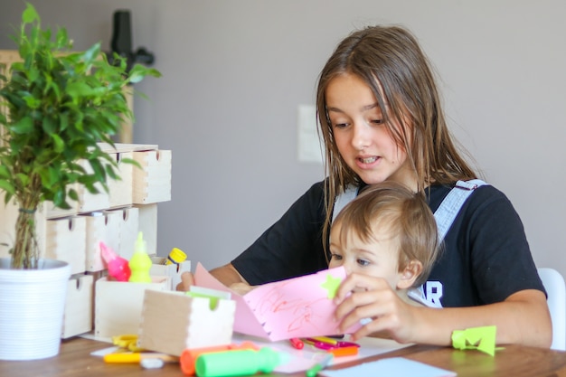 Foto giovane ragazza del preteen con il suo fratellino che crea biglietto di auguri di carta