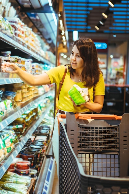 若いかなり大人の女性は食料品店で買い物をします