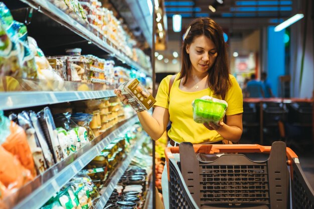 La giovane donna abbastanza adulta fa la spesa nel negozio di alimentari