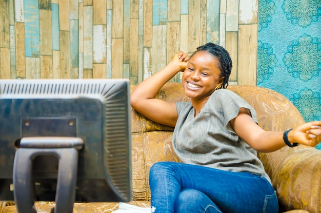 Молодая красивая африканская леди смотрит свою любимую телепрограмму Захватывающая черная женщина смотрит телевизор