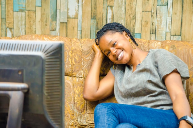 Young pretty african lady watching her favorite tv program\
exciting black woman watching tv