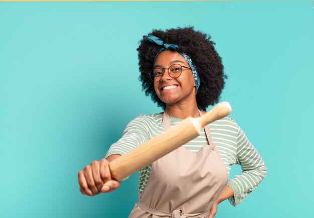 Young pretty afro woman chef with a rolling pin and pizzas