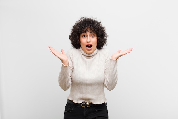 Young pretty afro woman feeling happy, excited, surprised or shocked, smiling and astonished at something unbelievable