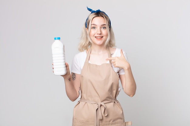 Young pretty albino woman feeling happy and pointing to self with an excited with a bottle of milk