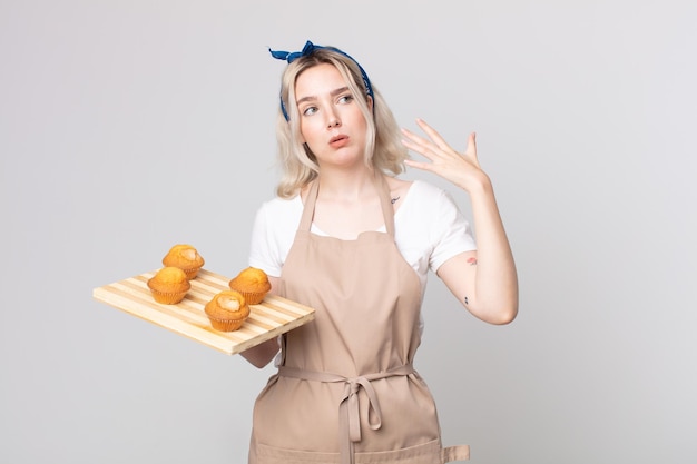 Giovane bella donna albina che si sente stressata, ansiosa, stanca e frustrata con un vassoio di muffin