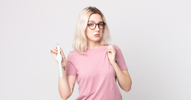 Young pretty albino woman looking arrogant, successful, positive and proud holding a watch clock