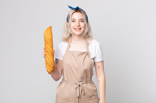 Young pretty albino woman looking happy and pleasantly surprised with a bread baguette