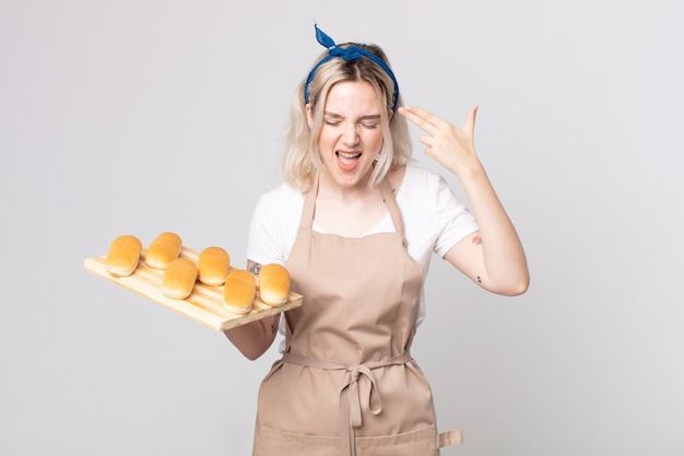 Young pretty albino woman looking unhappy and stressed, suicide gesture making gun sign with a bread buns tray