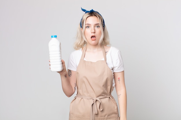 Young pretty albino woman looking very shocked or surprised with a bottle of milk