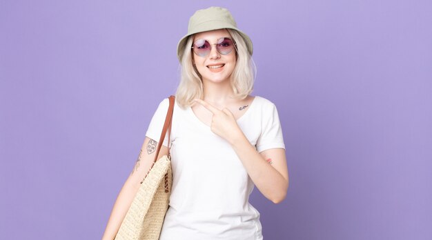 Young pretty albino woman smiling cheerfully, feeling happy and pointing to the side. summer concept