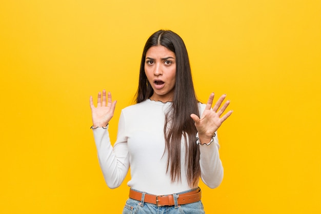 Young pretty arab woman against a yellow background being shocked due to an imminent danger