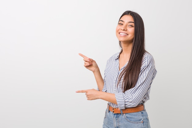 Young pretty arab woman excited pointing with forefingers away.