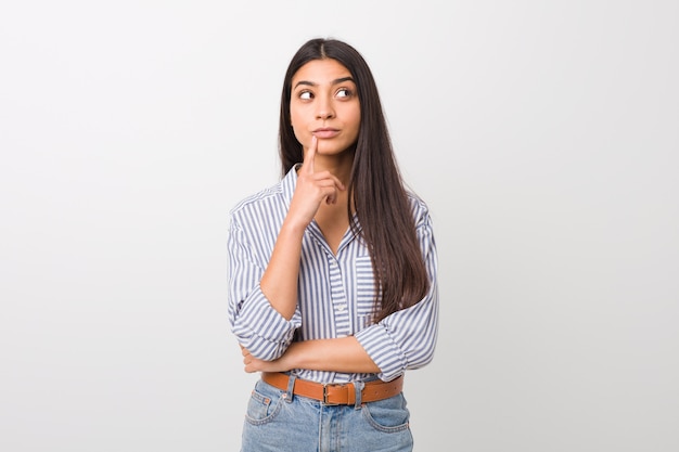 Young pretty arab woman looking sideways with doubtful and skeptical expression.