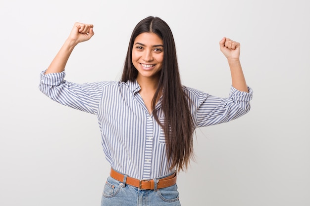 Young pretty arab woman showing strength gesture with arms, symbol of feminine power