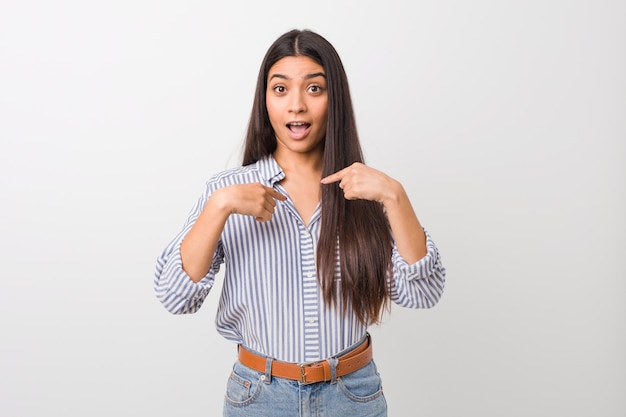 Young pretty arab woman surprised pointing with finger, smiling broadly.