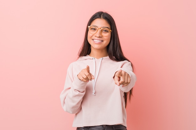 Young pretty arab woman wearing a casual sport look cheerful smiles pointing to front.