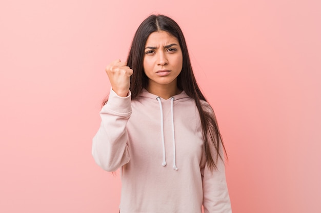 Young pretty arab woman wearing a casual sport look showing fist to camera, aggressive facial expression.