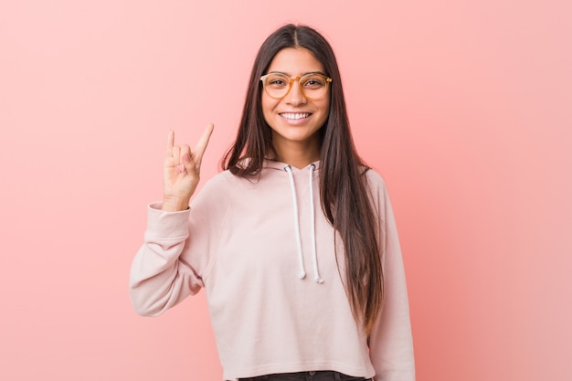 Young pretty arab woman wearing a casual sport look showing a horns gesture as a revolution concept.