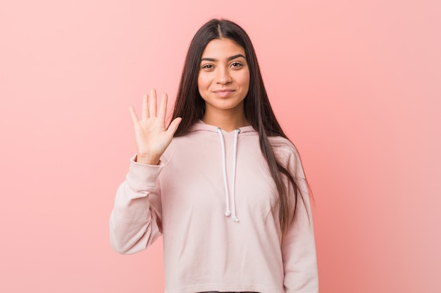 Young pretty arab woman wearing a casual sport look smiling cheerful showing number five with fingers.