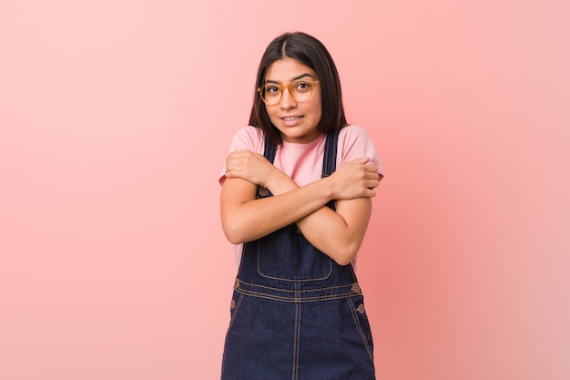 Young pretty arab woman wearing a jeans dungaree going cold due to low temperature or a sickness.