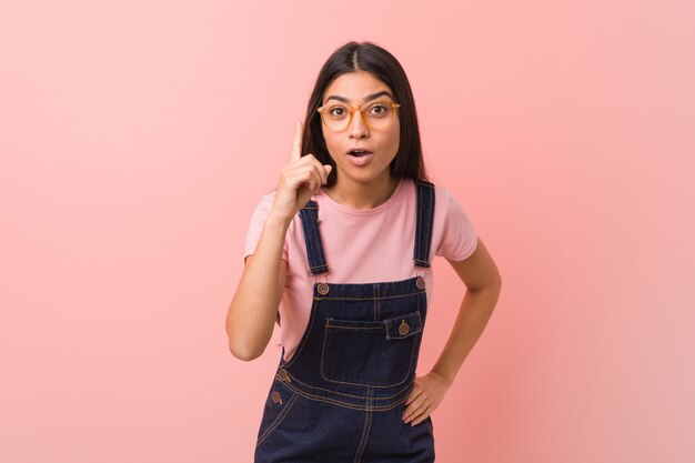 Young pretty arab woman wearing a jeans dungaree having an idea