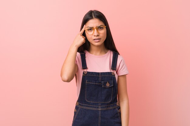 Young pretty arab woman wearing a jeans dungaree showing a disappointment gesture with forefinger.