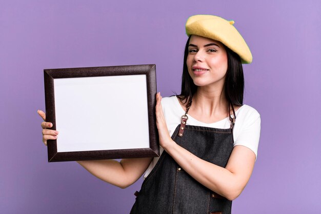 Young pretty artist showing an empty picture frame copy space