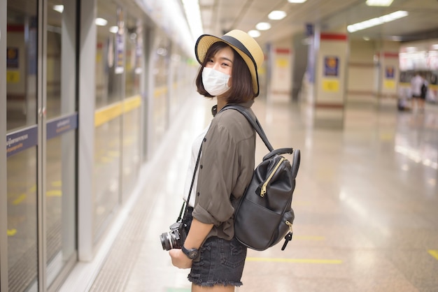 A young pretty Asian woman is wearing protective mask standing in metro station