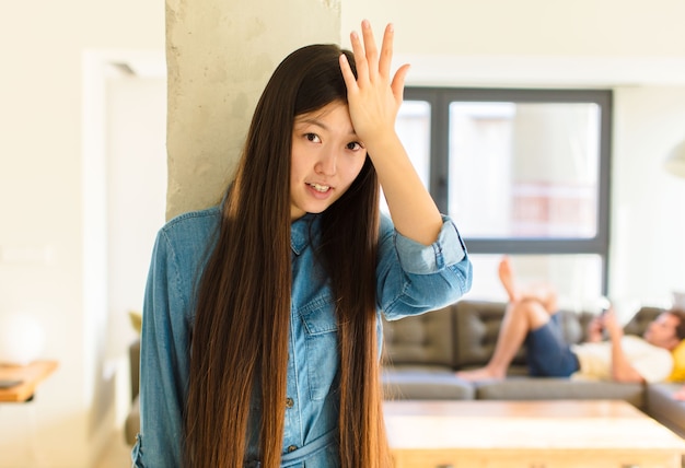 愚かな間違いをした後、または覚えている、愚かな感じの後、おでこを考えて手のひらを上げる若いかなりアジアの女性