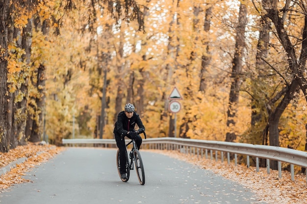 写真 秋の公園で自転車に乗って立っている美しいスポーツマン