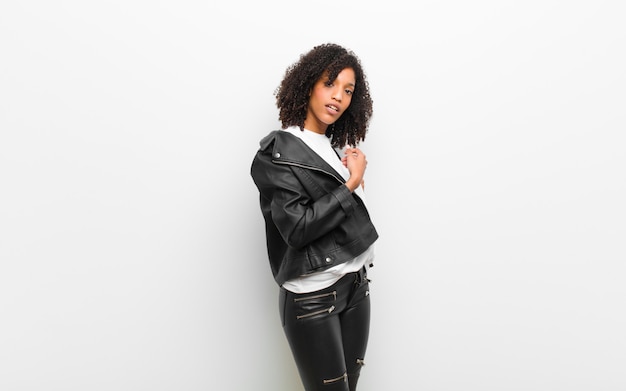 Young pretty black woman wearing a leather jacket against white wall