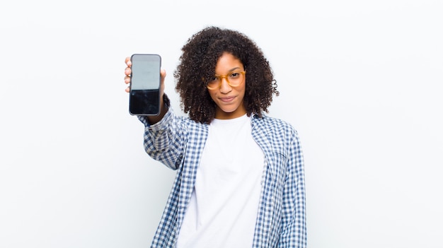 Young pretty black woman with a smart phone against white wall