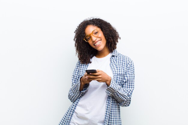 Young pretty black woman with a smart phone on white wall