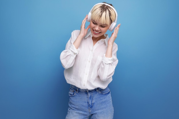 白いブラウスを着た若いかなり金髪の学生女性は、お気に入りの音楽を聴きます