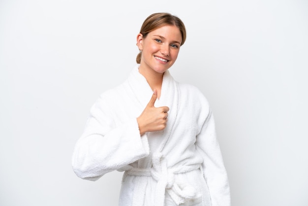 Young pretty blonde woman in bathrobe isolated on white background giving a thumbs up gesture